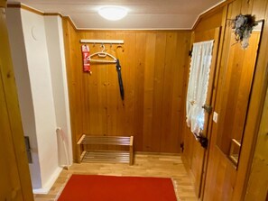Ein Zimmer mit Holzwänden, einer Bank, einem roten Teppich und einem Kleiderständer mit Bügel.