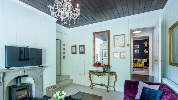 A living room with a fireplace, television, and a large mirror. - Gwynfryn House, Gorgeous Riverside Property Near The Beach (Llanbedr)