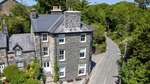 A stone building with multiple windows, a paved driveway, and a road adjacent to it. - Gwynfryn House, Gorgeous Riverside Property Near The Beach (Llanbedr)
