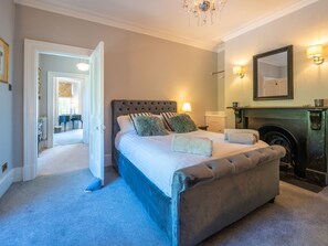 A bedroom with a large bed, a fireplace, and a mirror on the wall.