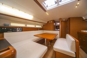 A compact interior with a central table, white cushioned seating, and a control panel. - Sun-kissed Sailing Adventure in Split-Dalmatia, Croatia (Seget Donji)