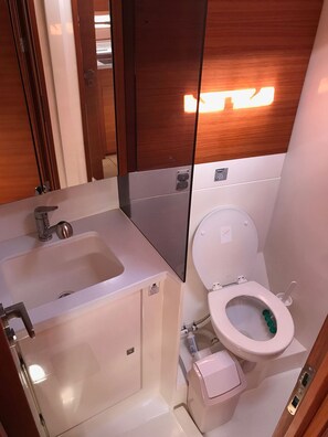A compact bathroom with a sink, toilet, and mirror.