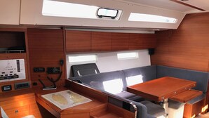 Espacio interior compacto con panel de control, cama, mesa y asientos.