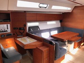 A compact interior with a control panel, a bed, a table, and seating.