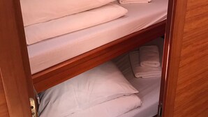 Una litera con ropa de cama blanca y un tragaluz arriba.