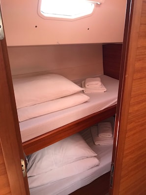 A bunk bed with white bedding and a skylight above.