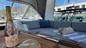 En lyxig inredning på en yacht med en soffa, en vinflaska och utsikt över hamnen.