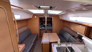 Un intérieur de camping-car compact comprenant un coin cuisine, un espace salon et des placards de rangement.