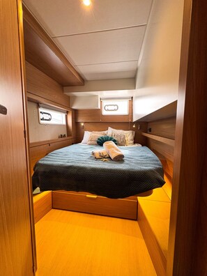 A compact, well-lit bedroom with a bed, wooden headboard, and a small window. - Sibenik Sun-soaked Sailing: A Luxurious Croatian Voyage (Pirovac)