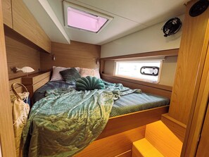 En kompakt indretning i en autocamper med seng, et vindue og et skydetag.