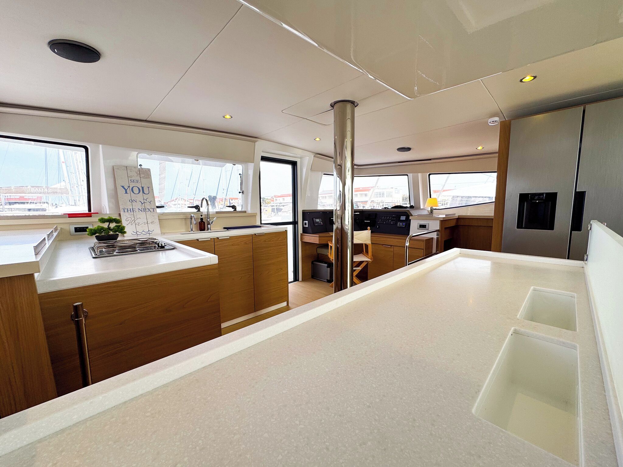 A modern kitchen with wooden cabinets, a central island, and a view of the city through large windows.