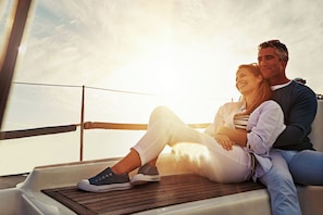 Un couple est assis sur le pont d’un bateau, avec vue sur l’eau.