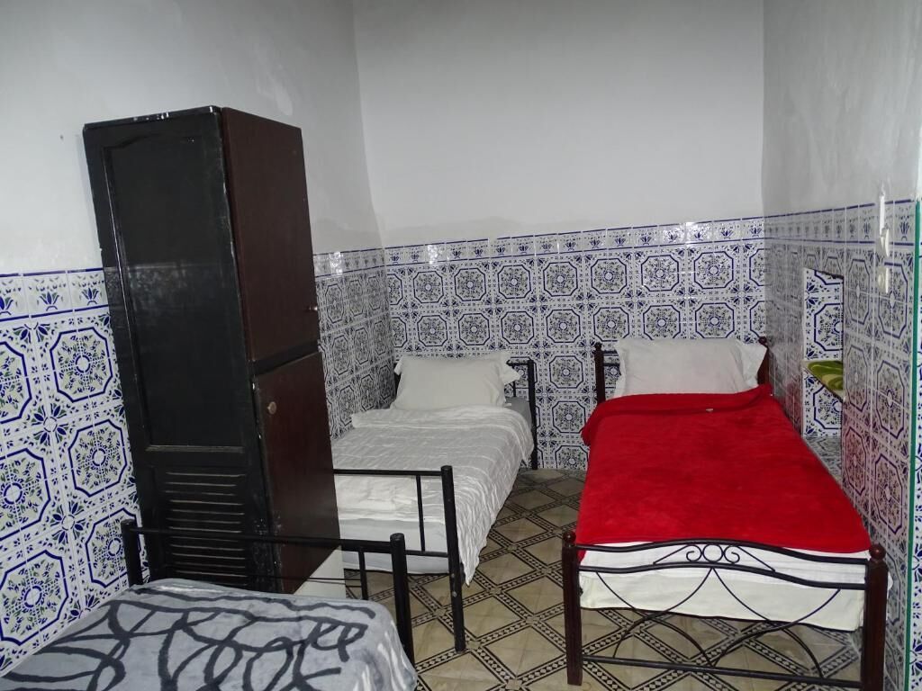 A small, compact room with a bed, a chair, and a wardrobe.