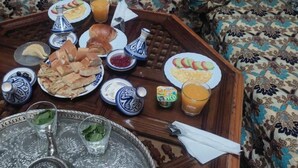 Um rico pequeno-almoço marroquino tradicional, servido numa bandeja com pão, pastelaria e um jarro de sumo.