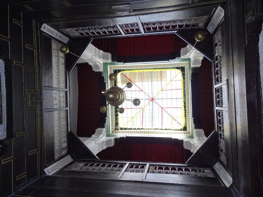 A room with a large window, a chandelier, and a red curtain.