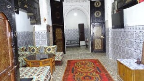 Um interior marroquino tradicional com um tapete estampado, móveis de madeira e trabalhos em azulejos detalhados.