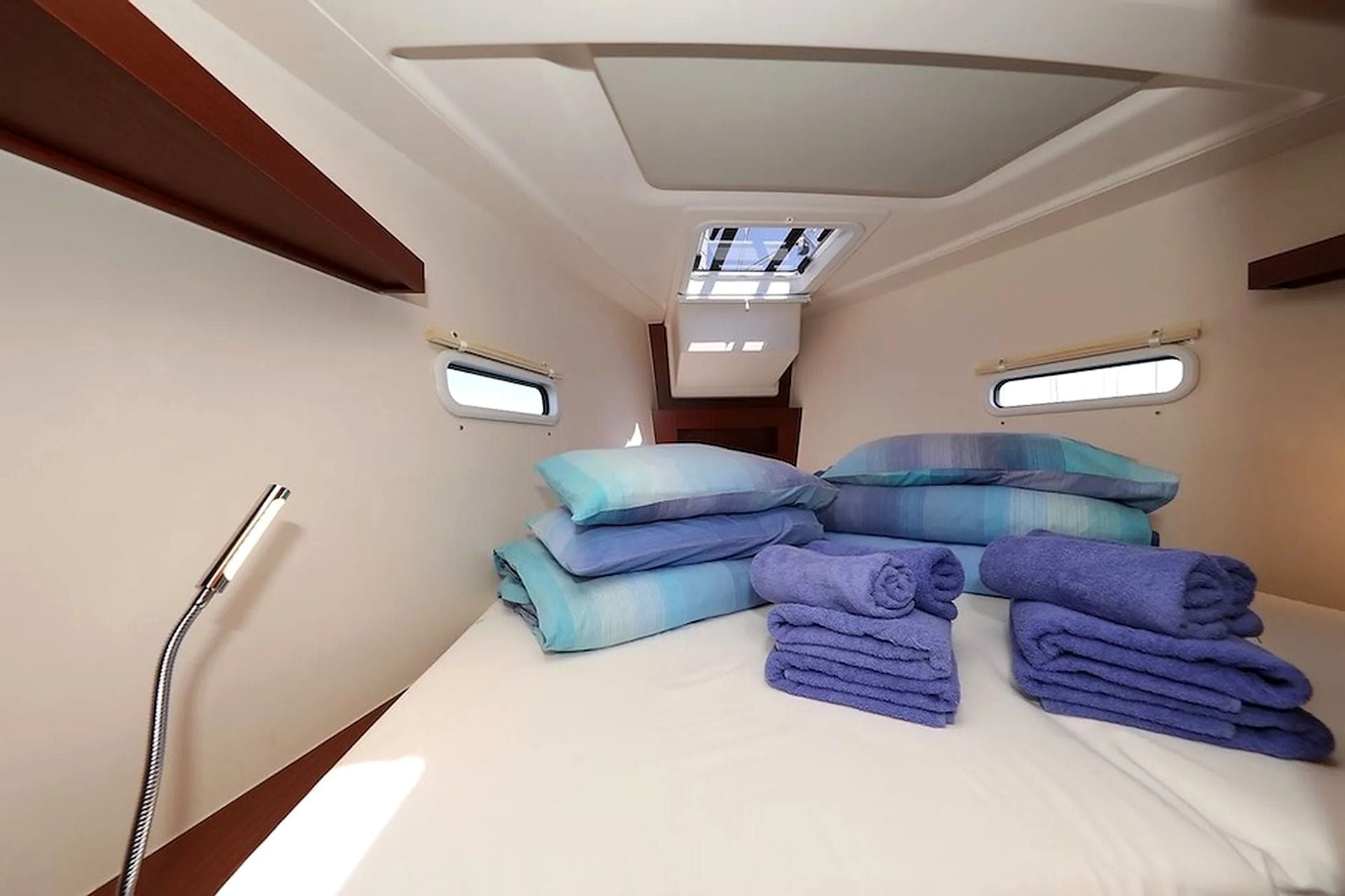 A compact room with a bed, two small windows, and a ceiling light fixture.