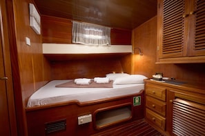 A compact cabin with a bunk bed, a small vanity with a mirror, and a cabinet with a handle.