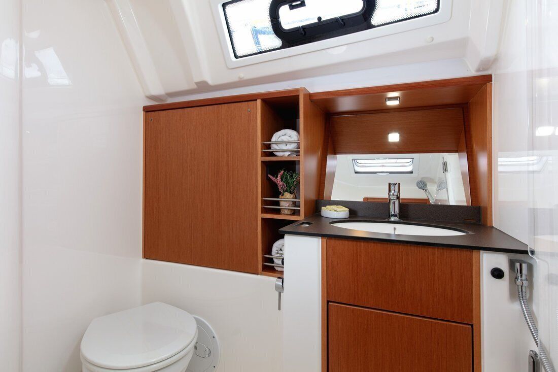 Ein kleines Badezimmer mit Toilette, Waschbecken mit Spiegel und Dusche.
