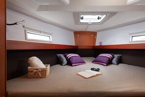 Ein kompaktes Wohnmobil-Interieur mit Bett, einer kleinen Sitzecke, einem Dachfenster und einem Fenster.