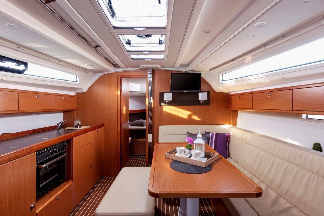 A compact galley with a stove, seating area, and a TV mounted on the wall.