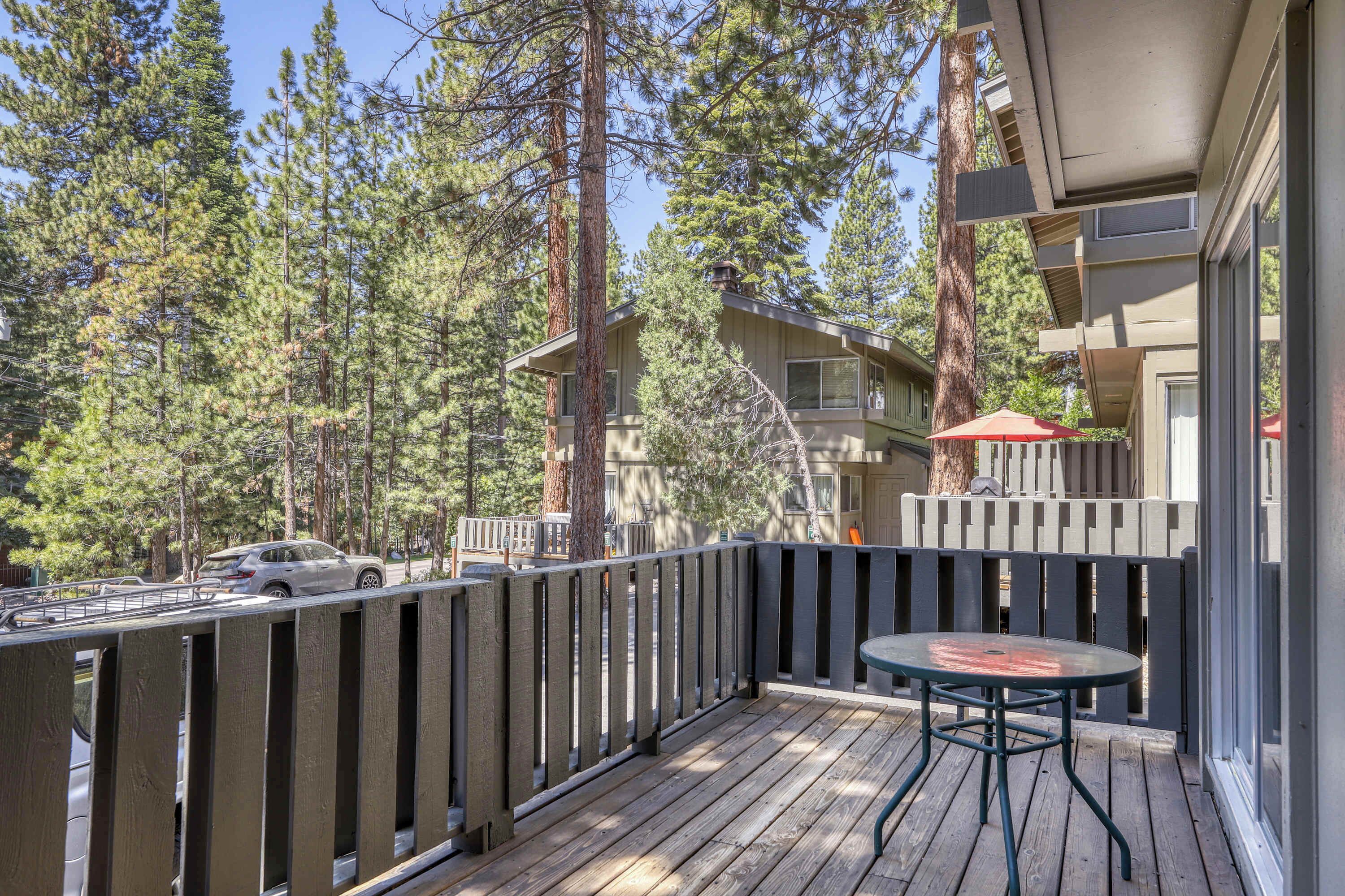 A balcony with a wooden railing, a table, and chairs.
