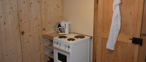 A compact kitchen with a white stove, a coffee maker, and wooden cabinets.