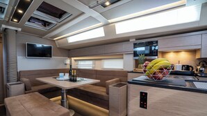 A modern RV interior with a dining area, kitchenette, and seating. - Sun-kissed Sailing Adventure in Split-Dalmatia, Croatia (Seget Donji)