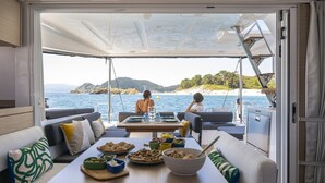 A dining area with a table set for two, a sofa, and a view of the sea. - Sun-kissed Sailing Adventure in Split-Dalmatia, Croatia (Seget Donji)