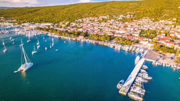 Vue aérienne d’une ville côtière avec un port de plaisance, des bateaux et des maisons.