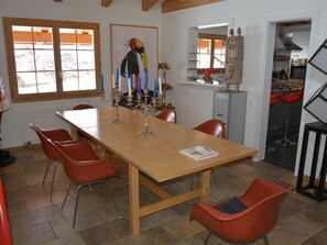 A dining area with a wooden table, red chairs, a candelabra, and a painting on the wall. - Scapa Appartement/Fewo, Dusche oder Bad, WC 4-Bettwohnung by Interhome (Gstaad)