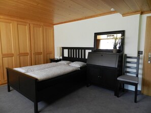 Ein Schlafzimmer mit Bett, Kommode, Stuhl und Spiegel.