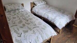 To enkeltsenge med et blomsterprint, træstel og en ensfarvet hvid væg.