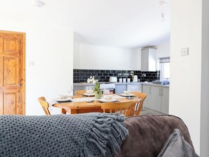 Una cocina moderna con comedor, que incluye una puerta de madera, una mesa de comedor con platos y vasos, y una encimera de cocina con electrodomésticos.
