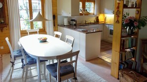 Eine gemütliche Küchenzeile im Chalet-Stil mit einer zentralen Kochinsel, weißen Schränken und einem Essbereich mit Tisch und Stühlen.