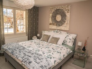 Ein Schlafzimmer mit einem Bett, einem Nachttisch, einer Lampe und einem Wandbild.