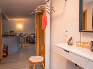 Ein Hotelzimmer mit weißem Schminktisch, einem Spiegel, einem kleinen Holzstuhl, einem Handtuchhalter und einem Willkommensschild.