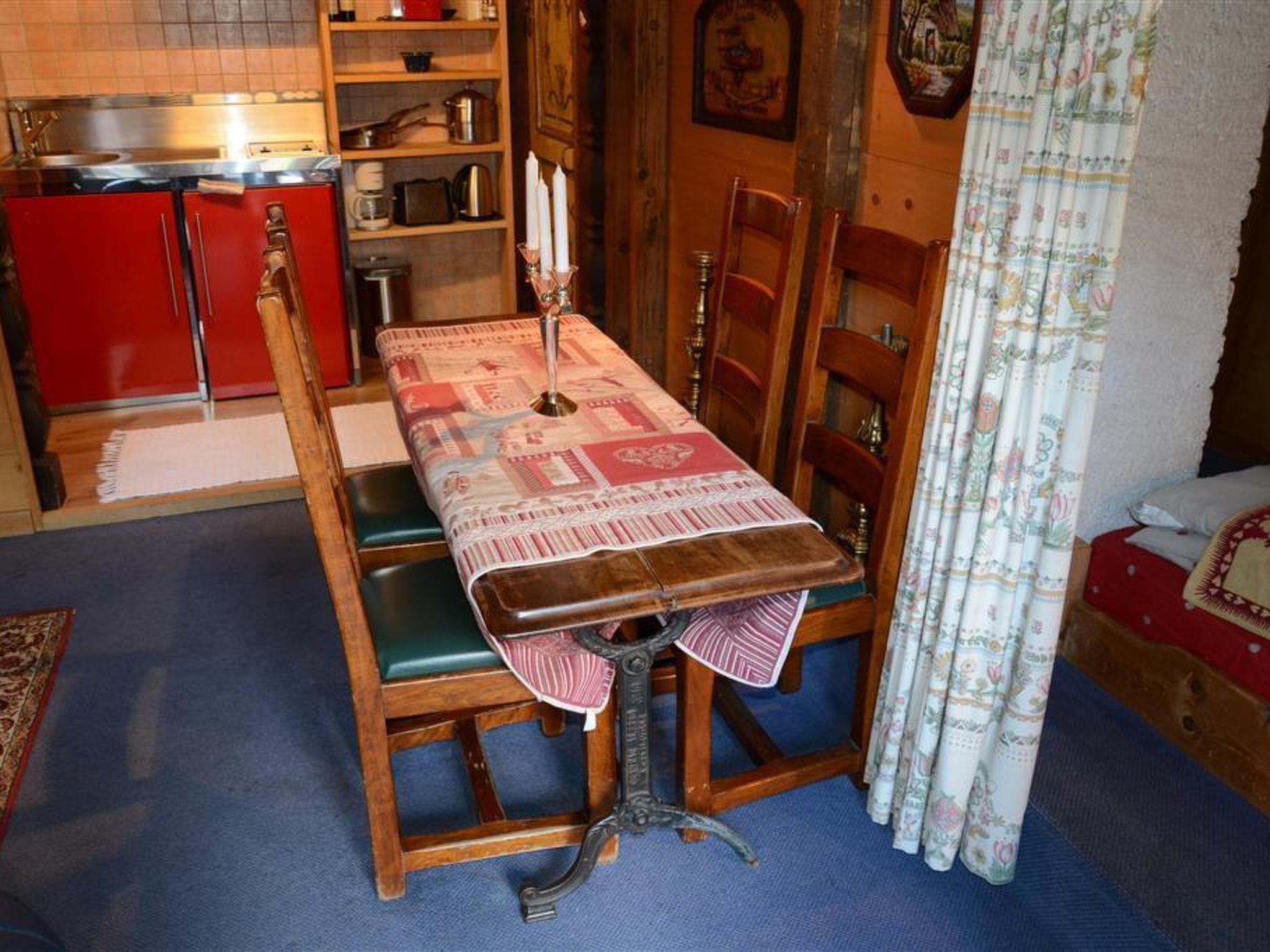 Un coin repas avec une table en bois, des chaises et une nappe à motifs.