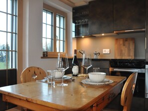 Un coin repas avec une table en bois dressée pour deux personnes, une bouteille de vin et une machine à café.