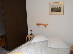 A bedroom with a bed, a nightstand, a desk, a wardrobe, and a framed picture on the wall. - Mireille Nr. 3 Appartement/Fewo, Dusche oder Bad, WC 2-Bettwohnung by Interhome (Gstaad)