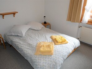 A single bed with a patterned bedspread, two pillows, a bedside table with a lamp, and a radiator. - Mireille Nr. 3 Appartement/Fewo, Dusche oder Bad, WC 2-Bettwohnung by Interhome (Gstaad)