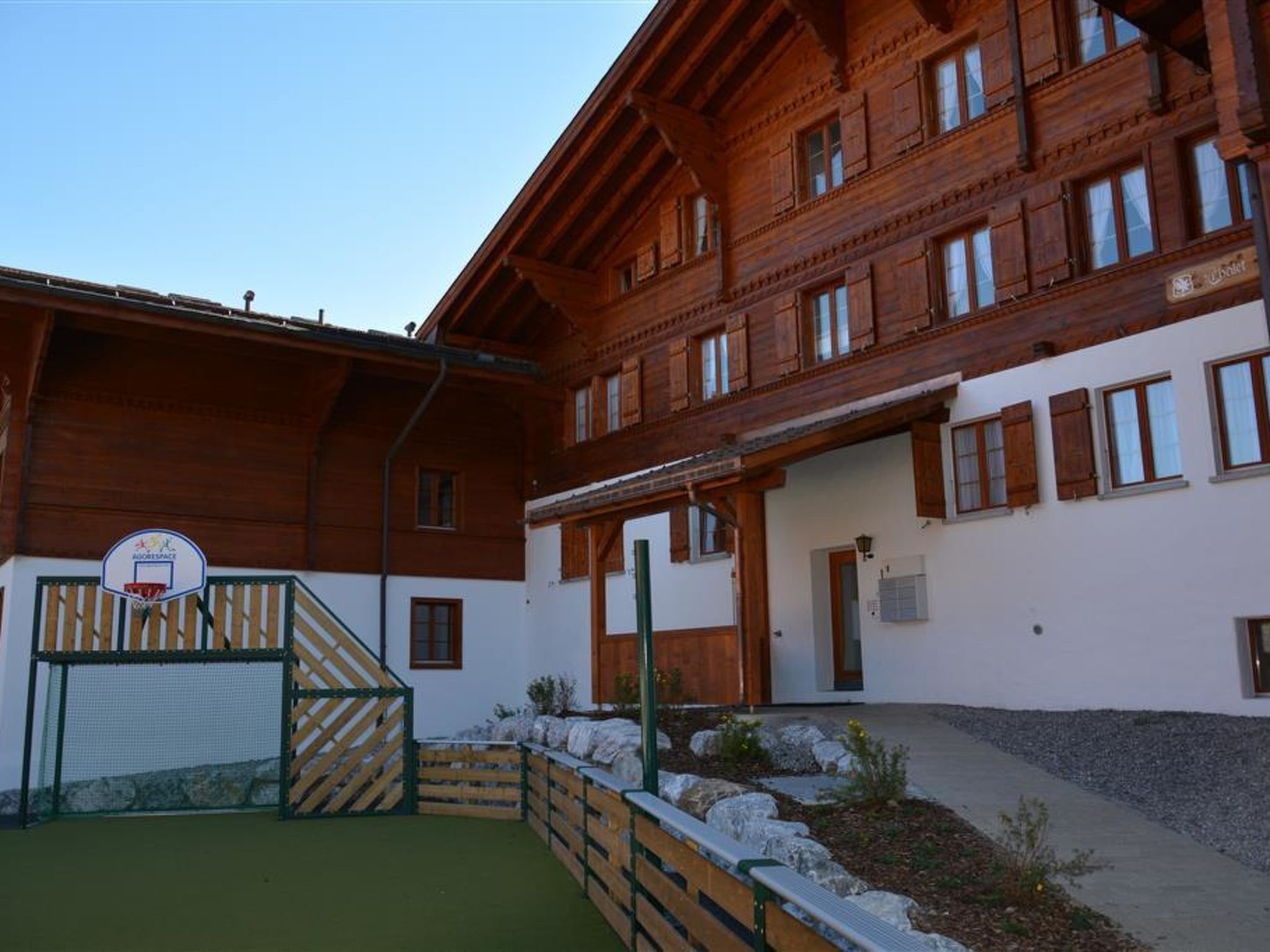 Ein Holzgebäude mit mehreren Fenstern und einem Basketballplatz.