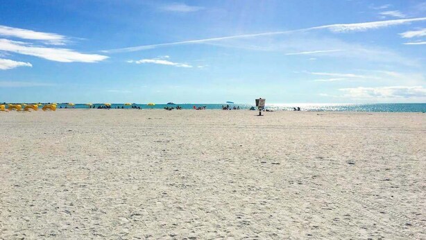 A beach with umbrellas and a lifeguard tower. - Cozy Condo, Steps to St. Pete Beach + Shared Pool (St. Petersburg Beach)