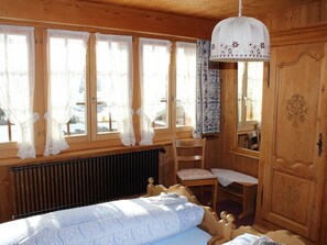 A wooden room with a bed, a chair, a table, and a wardrobe. - Beatrice Appartement/Fewo, Dusche oder Bad, WC 7-Bettwohnung by Interhome (Gstaad)