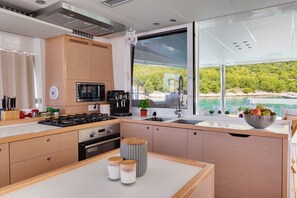 A modern kitchen with a large window, a stove, microwave, and a sink. - Sun-Kissed Sailing Adventure in Split-Dalmatia, Croatia (Marina)