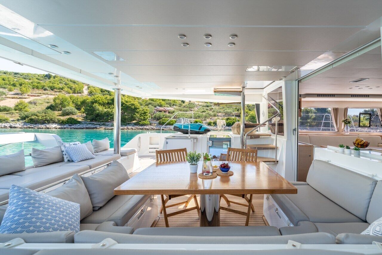 A yacht interior with a dining area, seating, and a view of the sea.
