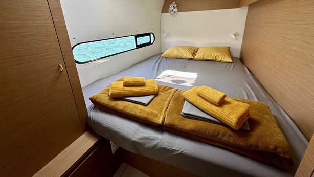 Ein gemütlicher Raum mit Bett, Fenster mit Blick und einem kleinen Wandventilator.