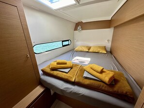 Une petite chambre comprenant un lit, une fenêtre donnant sur un beau paysage et un petit ventilateur fixé au mur.