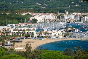 A coastal marina with numerous boats, a sandy beach, and residential buildings with balconies.