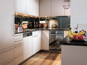 A modern kitchen with white cabinets, a black countertop, and a wooden floor. - Haus Sunneschy Whg. 202 Appartement/Fewo, Dusche, WC 2.5  Zimmerwohnung/ Whg.202 by Interhome (Parpan)